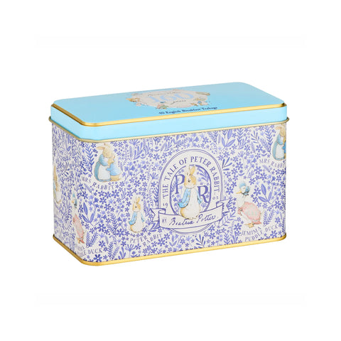 A rectangular metal tin with a light blue lid and a blue-and-white floral patterned body featuring Peter Rabbit illustrations and a central crest, photographed on a plain white background.