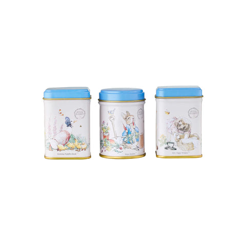 Three tea tins with Beatrix Potter themed illustrated lids on a white background