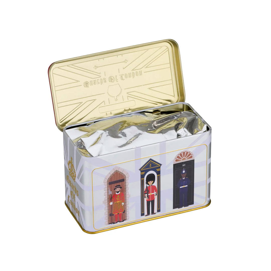 An open rectangular metal tin with a gold-toned lid and base, featuring a Union Jack pattern and illustrations of three British police box guards on the front. The tin is filled with silver foil packaging and photographed on a plain white background.