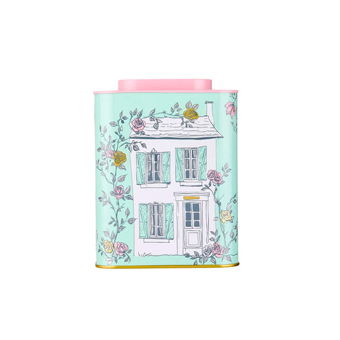 Tea canister with a house and floral design on a light blue background