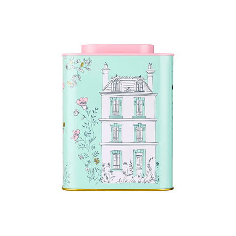 Decorative tea canister with a pink lid and house illustration on a light blue background