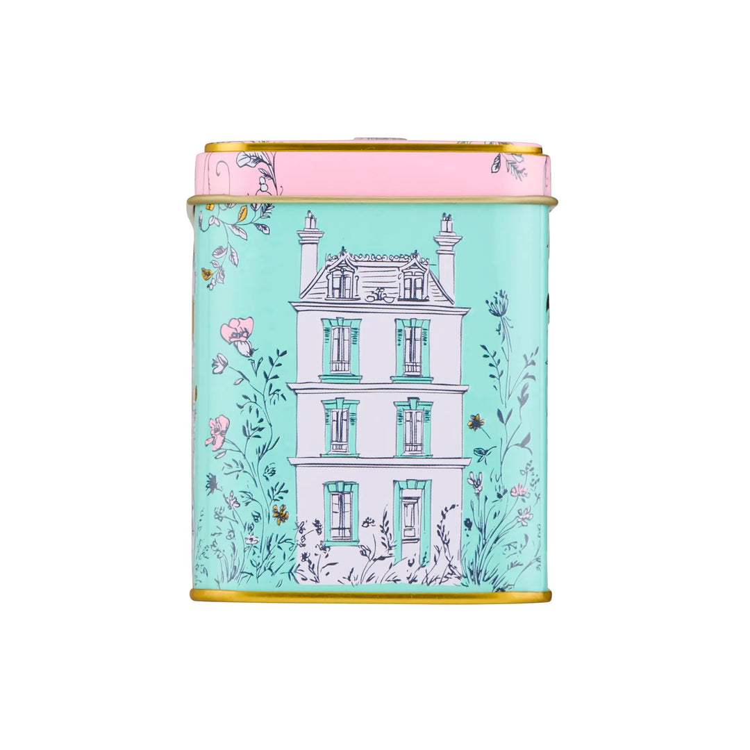 Decorative tea tin with house and floral design on a light blue green background