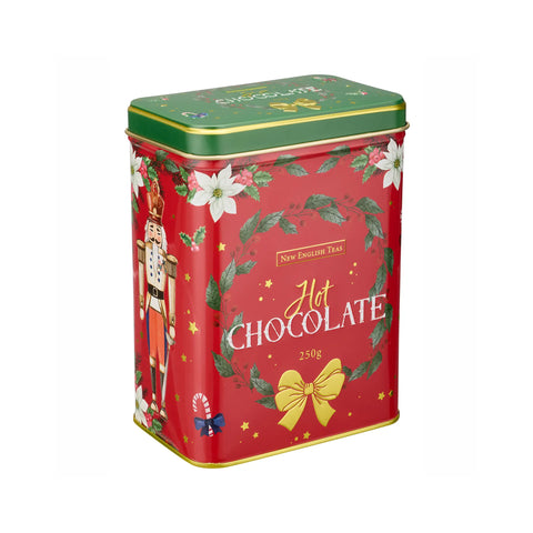 A square red metal tin of New English Tea Hot Chocolate, decorated with a green top lid, white poinsettias, a nutcracker, and a gold bow on a white background.