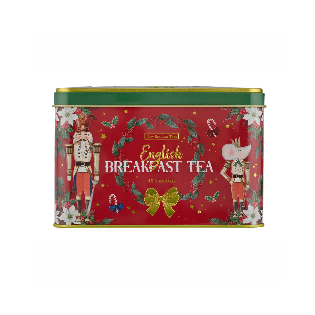 A rectangular red tin of New English Teas English Breakfast Tea, decorated with festive Christmas illustrations including nutcrackers, a green wreath, white flowers, and a gold bow.