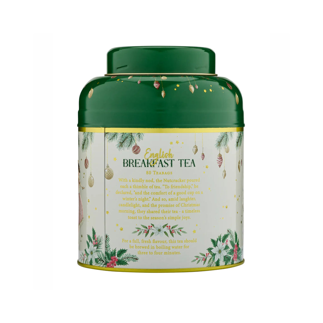 A cylindrical metal tea tin with a dark green lid and base, featuring a cream-colored label decorated with festive green pine branches, red berries, gold ornaments, and gold text that reads 'English Breakfast Tea'.
