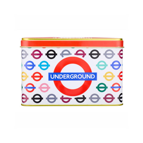 A rectangular metal tin with a lid, featuring a white label printed with the London Underground roundel logo in multiple colors and a large red-and-blue Underground emblem in the center. The lid has a red band with gold trim.